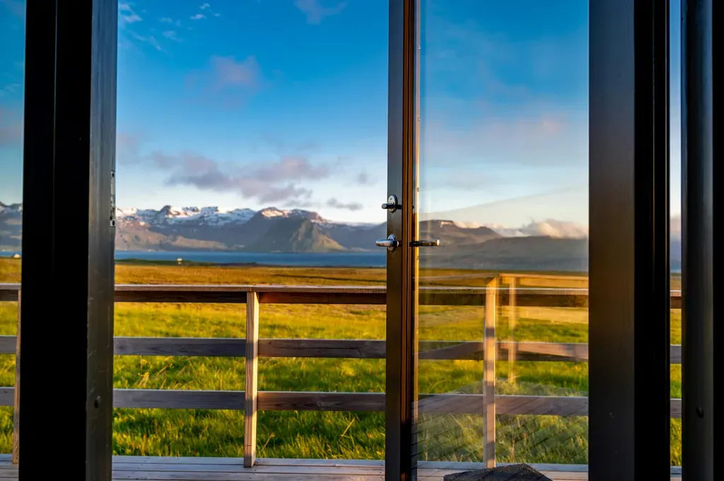 An open door leading to a field with mountains in the background