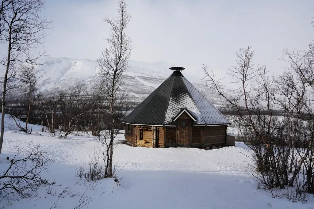 Traditional Scandinavian hut surrounded by snowy landscape in Norrbottens län, Sweden.
