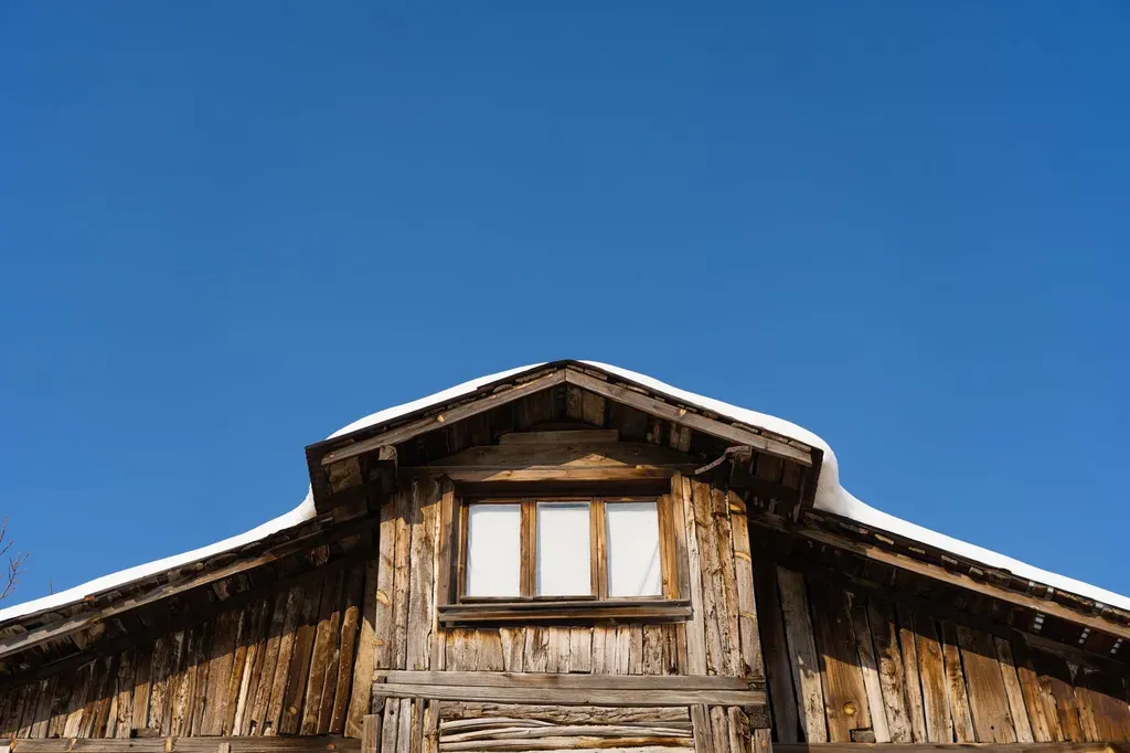 Low angle view of a wooden cabin roof with snow and clear blue sky in Mudurnu, Türkiye.