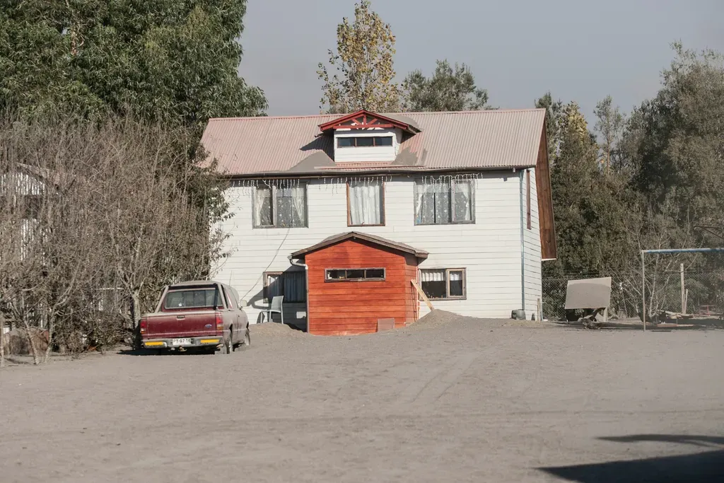 A house and car covered in volcanic ash